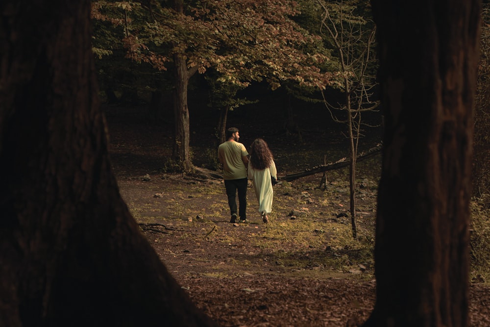 a man and a woman walking through a forest