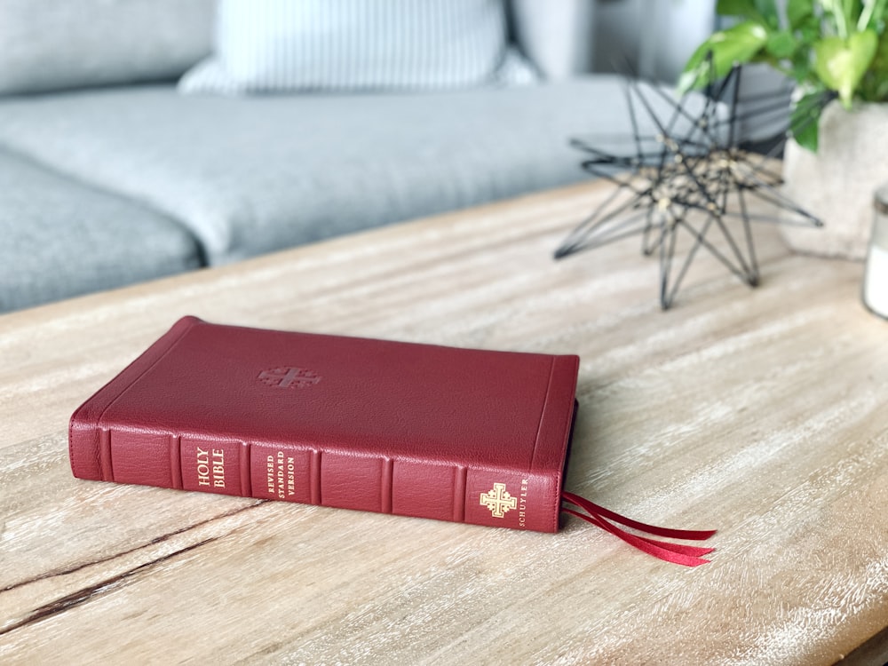 um livro vermelho sentado em cima de uma mesa de madeira
