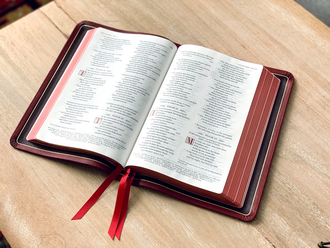 an open book on a table with a red ribbon