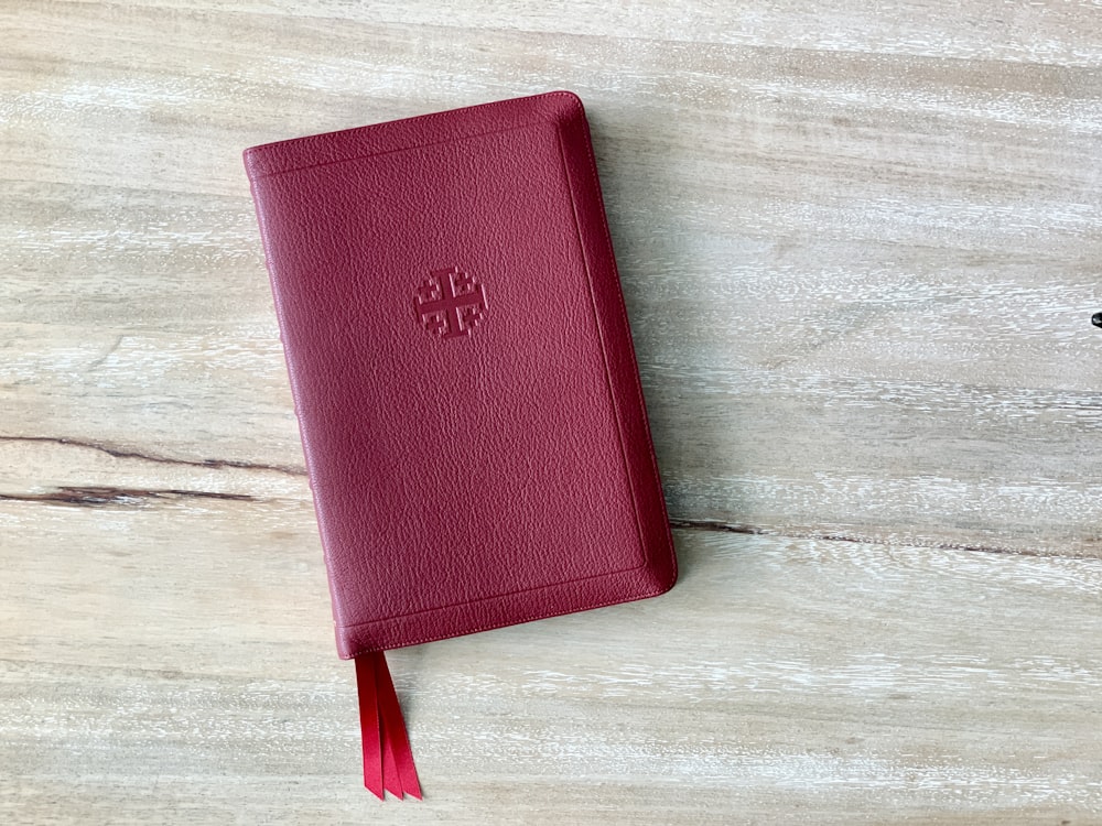 un livre rouge avec un gland sur une table en bois
