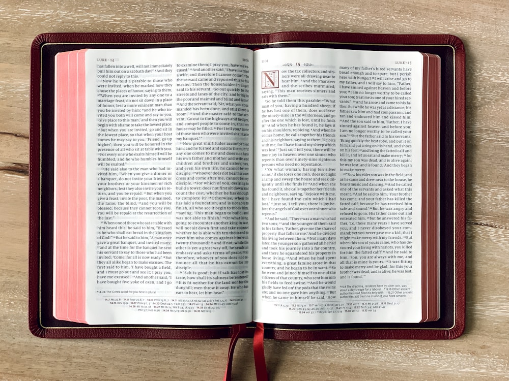 an open book with a red ribbon on a wooden table