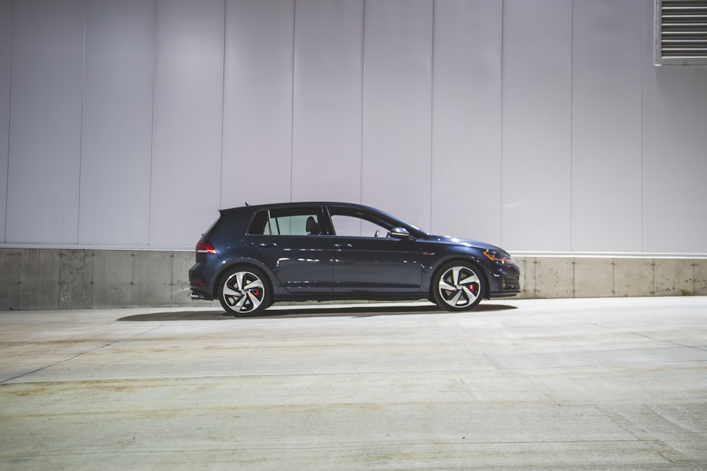 a blue car parked in front of a white wall