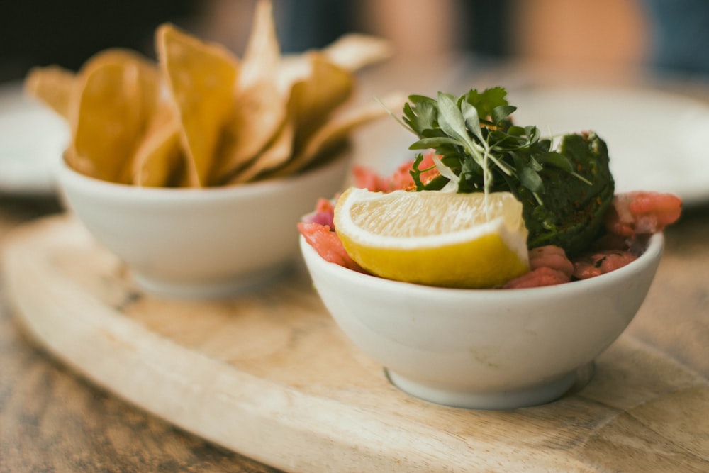 a white bowl filled with food next to a plate of chips