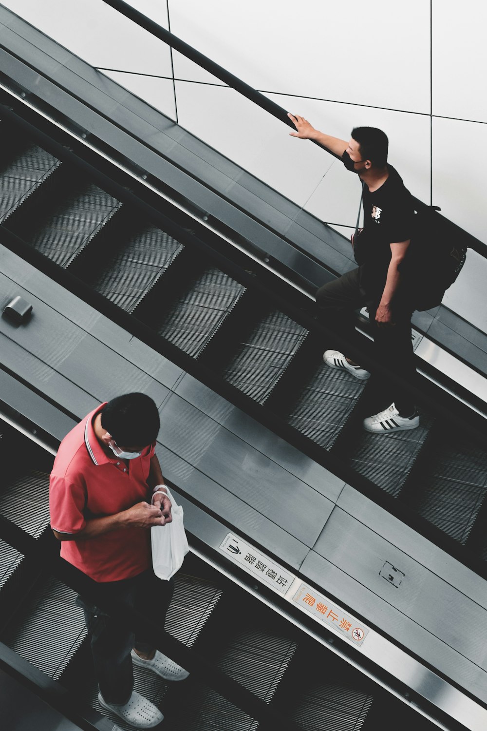 a man standing on an escalator pointing at another man