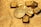 A collection of gold bullion including bars and coins, featuring intricate designs and inscriptions visible on the surfaces. The items are placed on a textured golden background, emphasizing their shiny and luxurious appearance.