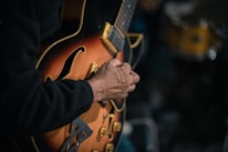 Close-up of hands playing blues guitar chords on a sunburst electric guitar.
