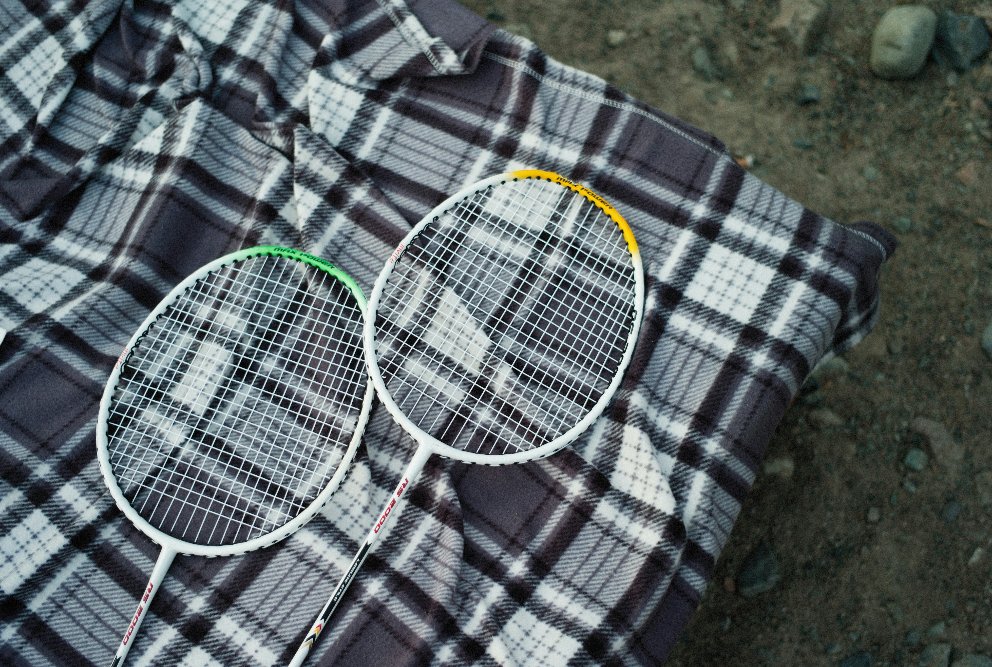 two tennis rackets laying on a plaid shirt