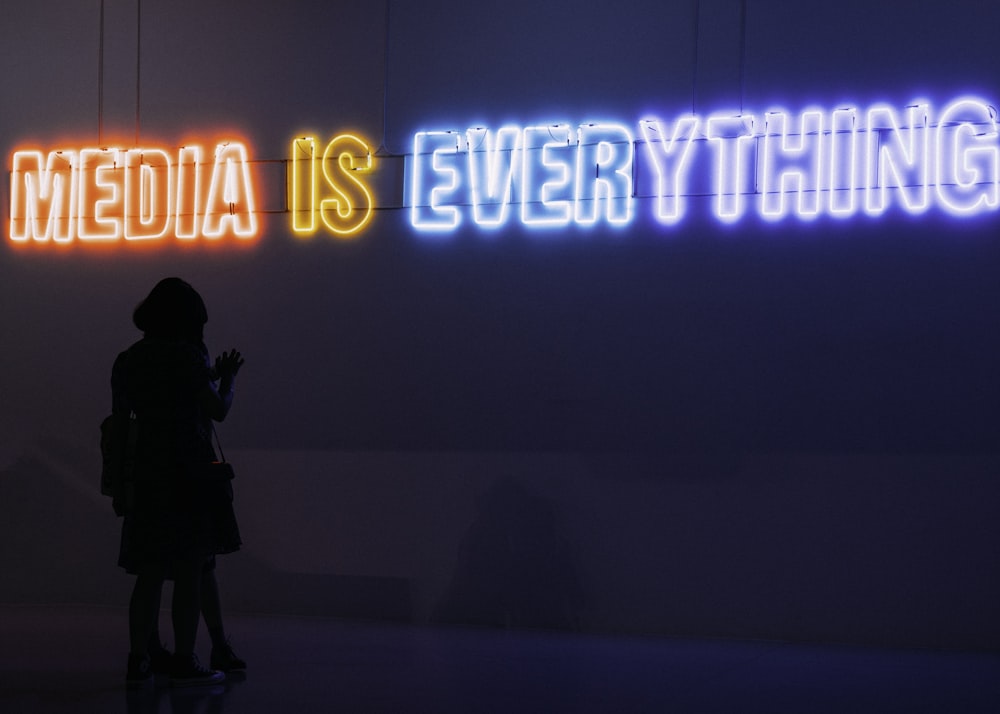 a person standing in front of a neon sign