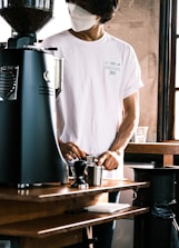 a man wearing a face mask while preparing a drink