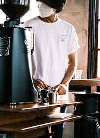 a man wearing a face mask while preparing a drink