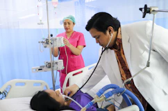 a man laying in a hospital bed being examined by a nurse