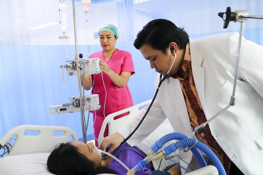 a man laying in a hospital bed being examined by a nurse