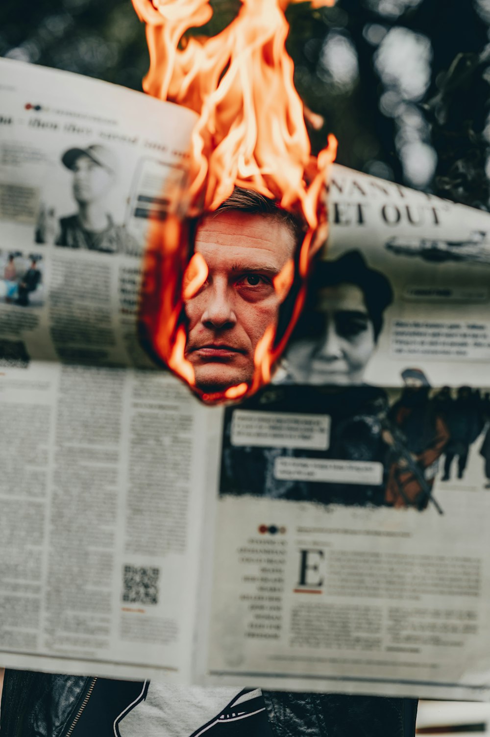 a man reading a newspaper with a fire in the background