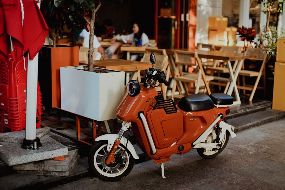 an orange scooter parked in front of a restaurant