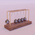 A Newton's cradle with chrome spheres on a rustic wooden base