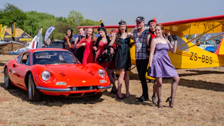 Vintage portrait of a group of people dressed in period clothing gathered around a classic car