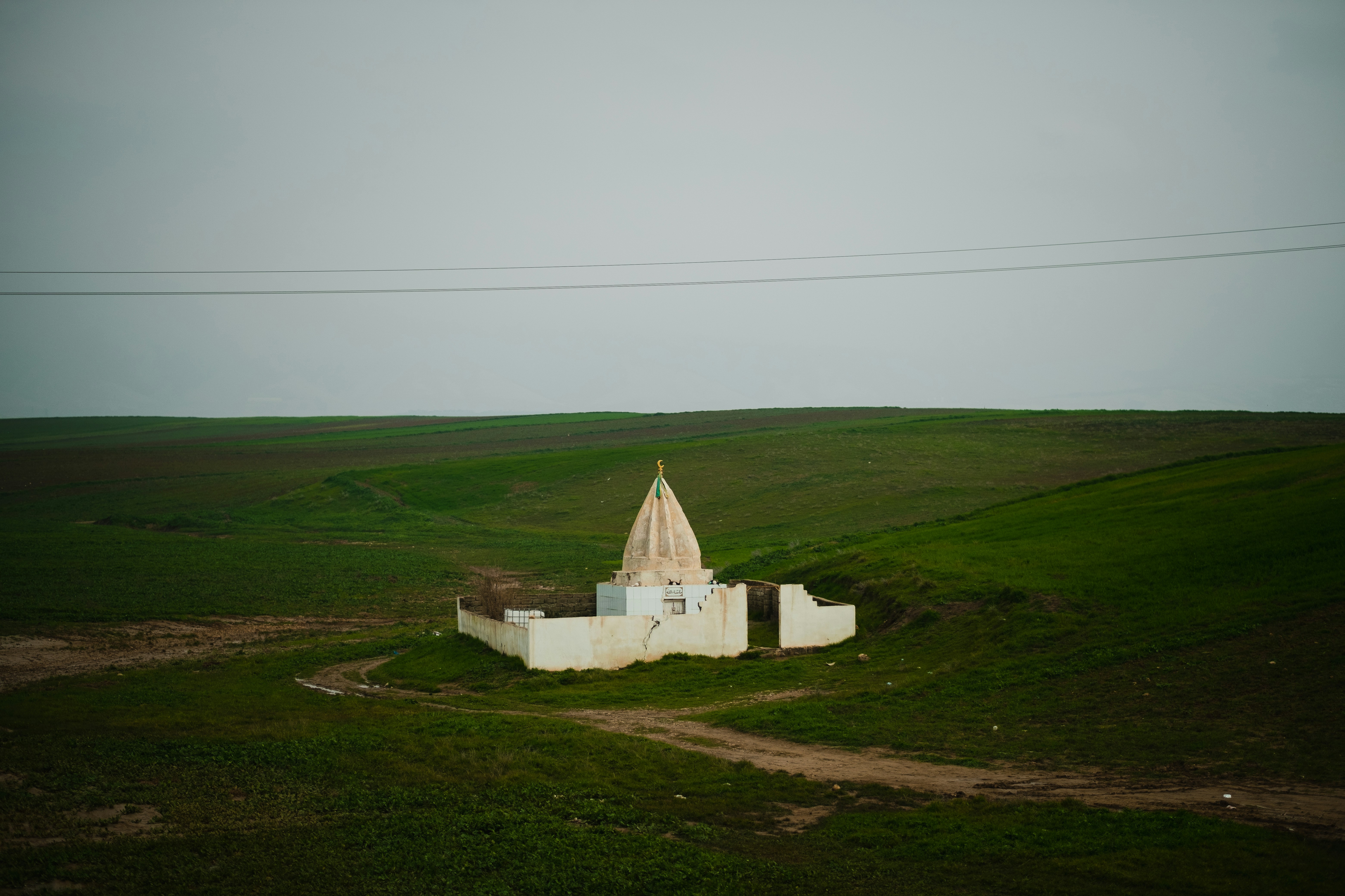 a small white building in a green field
