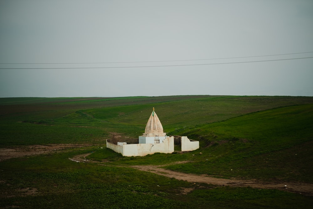 a small white building in a green field