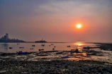 Sunset over the Arabian Sea with silhouettes of fishing boats near the shore.
