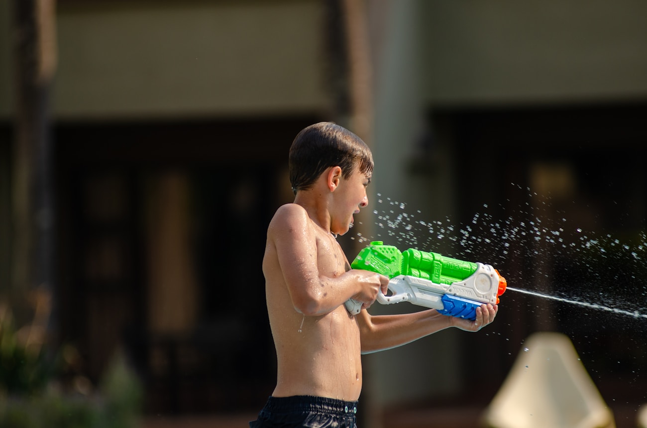 Young boy having fun playing with a water gun on a hot day