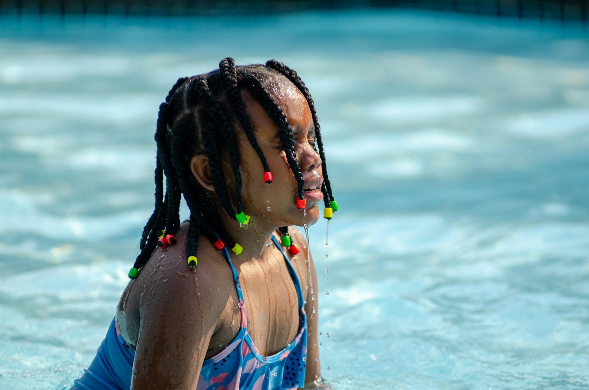 a little girl in a pool with a frisbee in her mouth