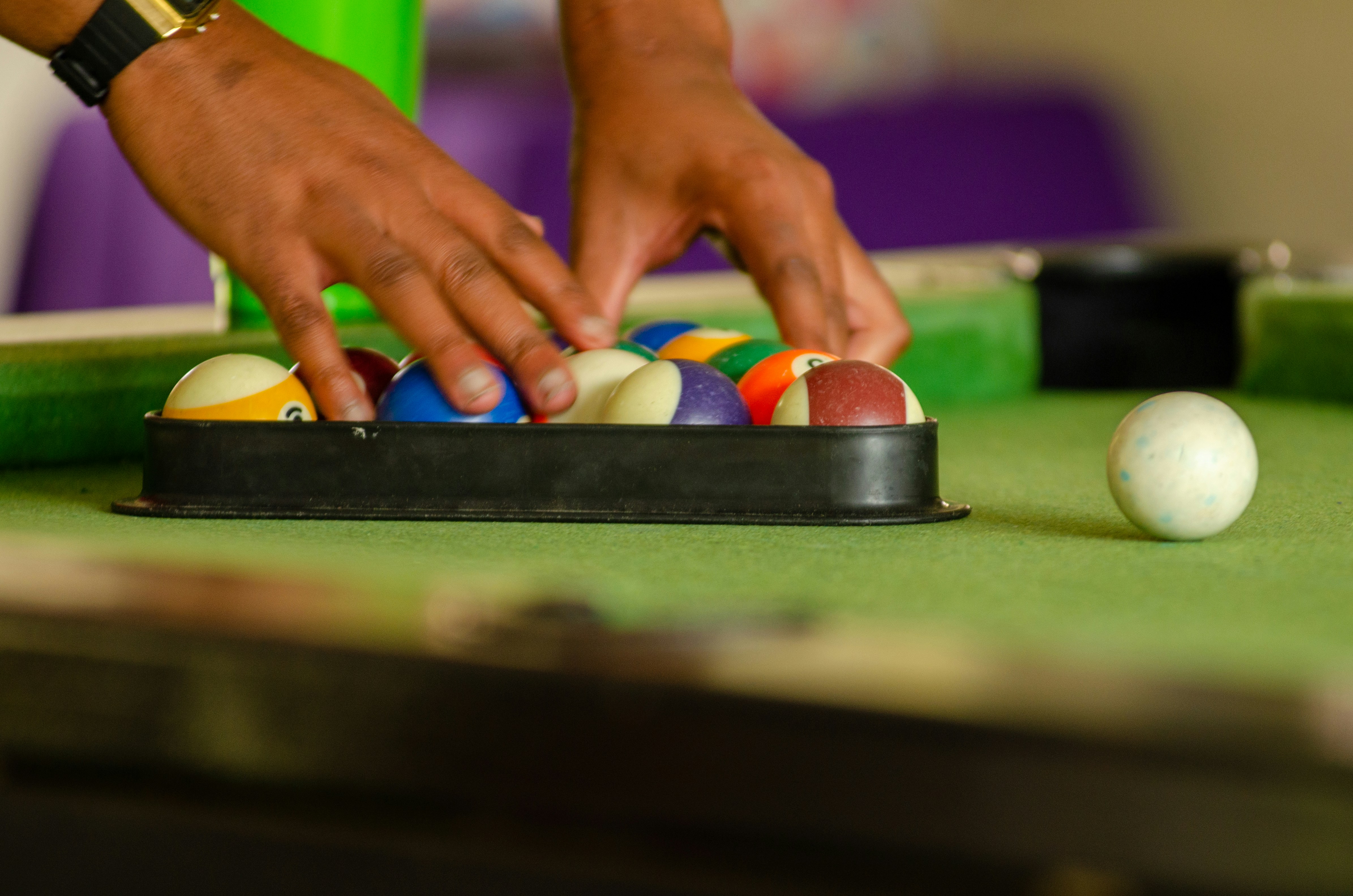 a person reaching for a ball on a pool table