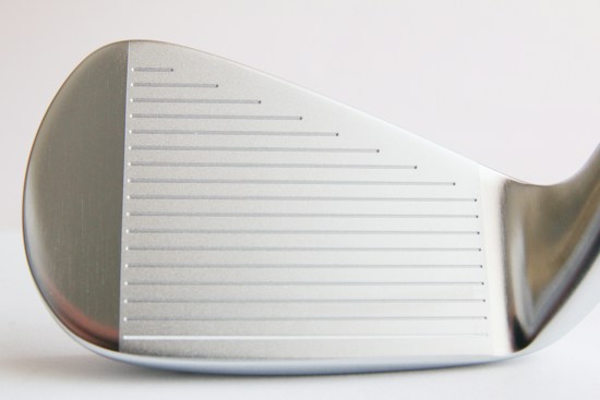Close-up view of a metallic golf club head with visible grooves and a smooth silver surface, showing intricate craftsmanship and detailing.