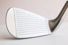 Close-up of a clean, shiny golf iron head against a pale background