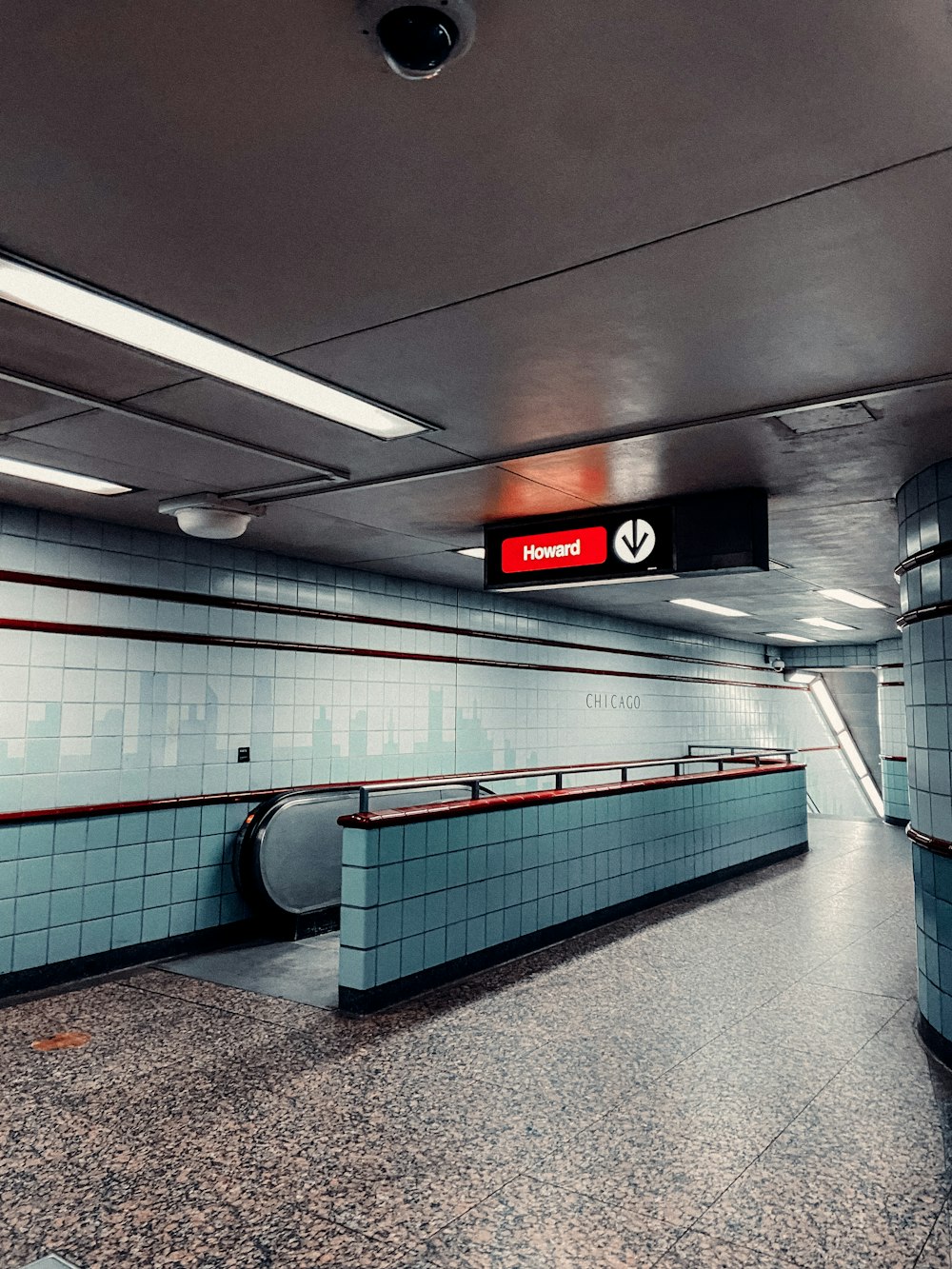 a subway station with blue tiled walls and a red sign