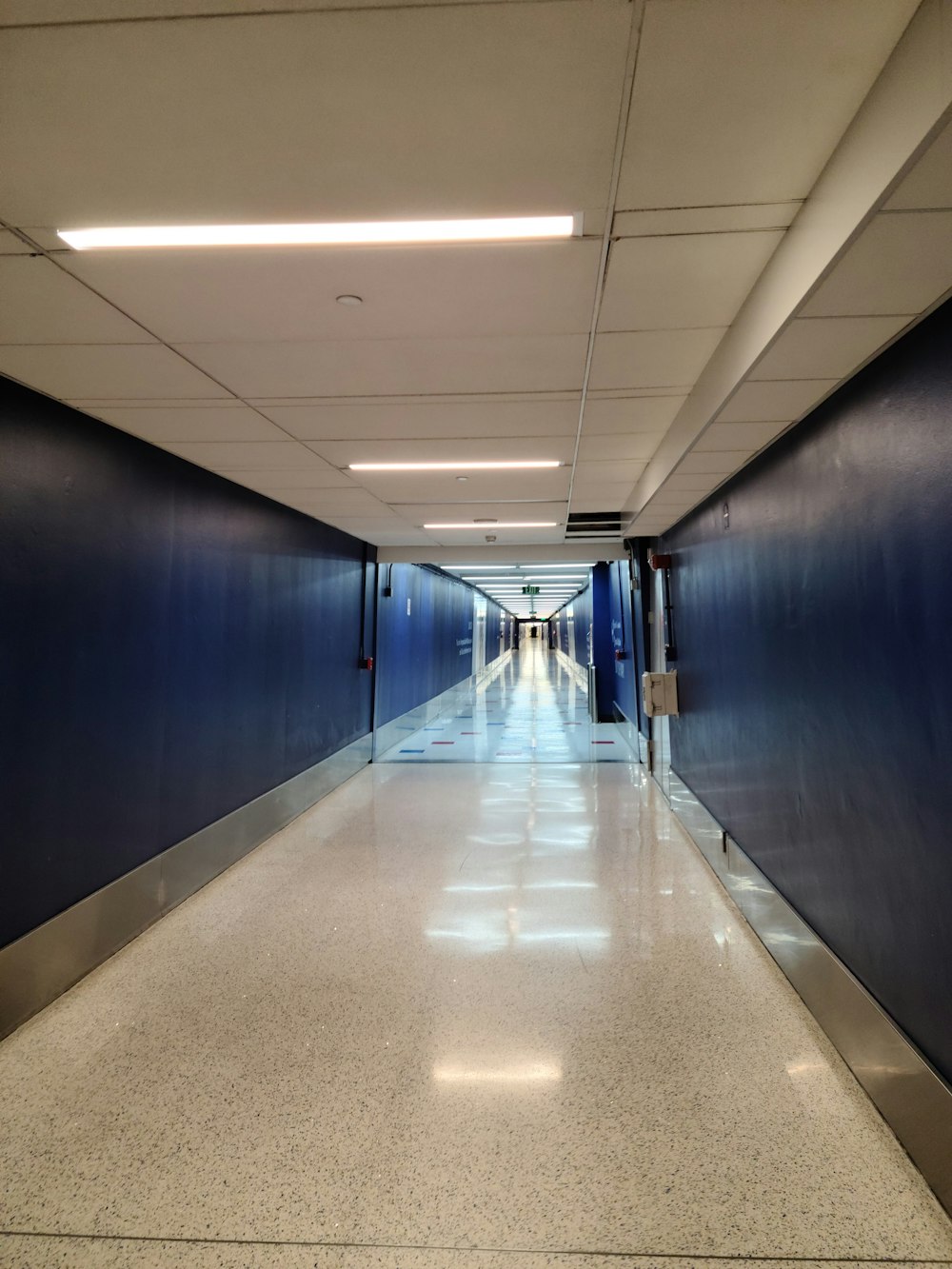 a long hallway with blue walls and a white floor