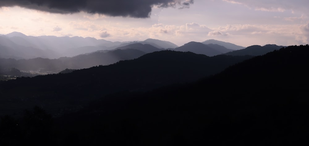 the sun is shining through the clouds over the mountains