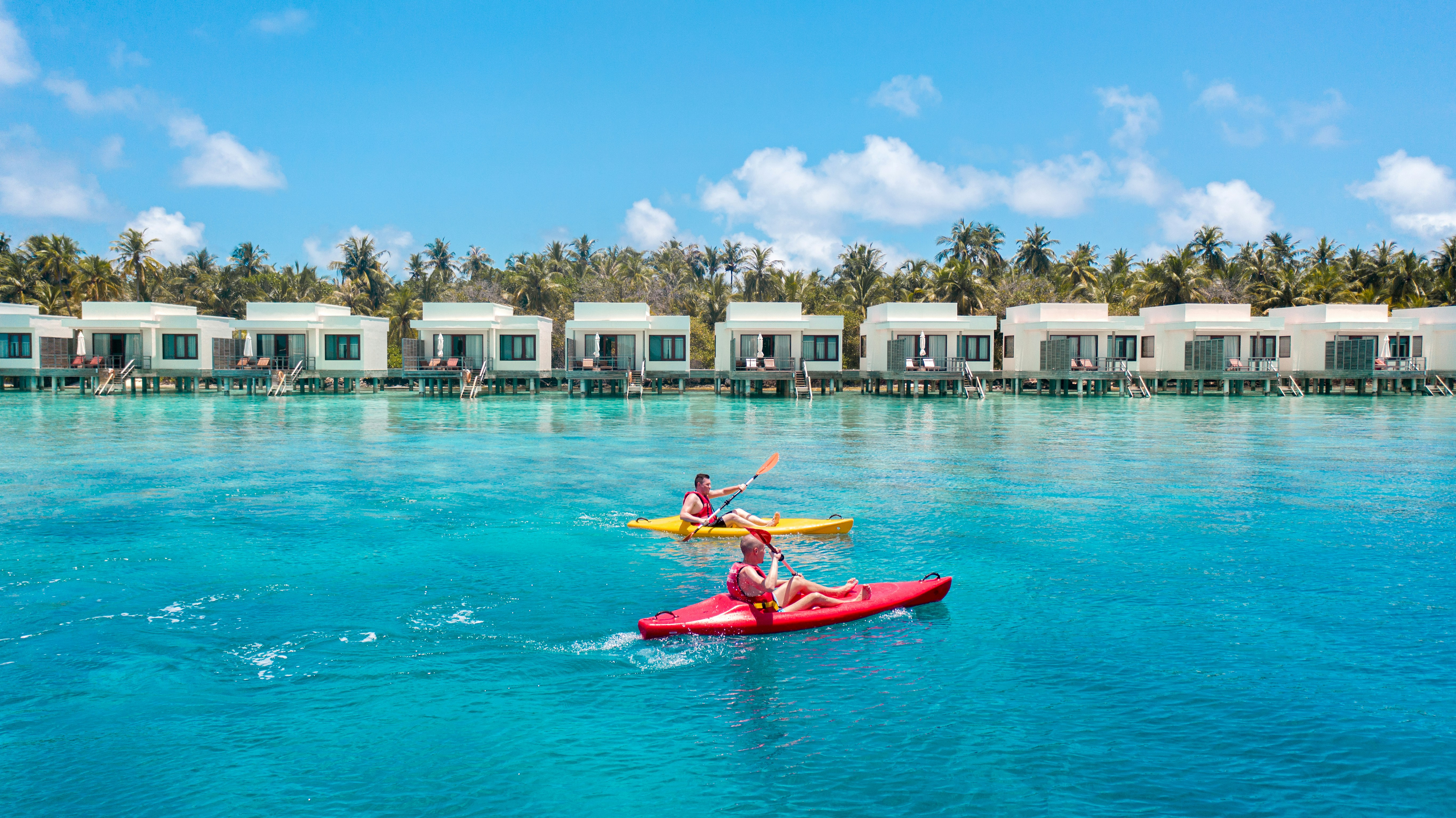 a couple of people riding on top of a red kayak
