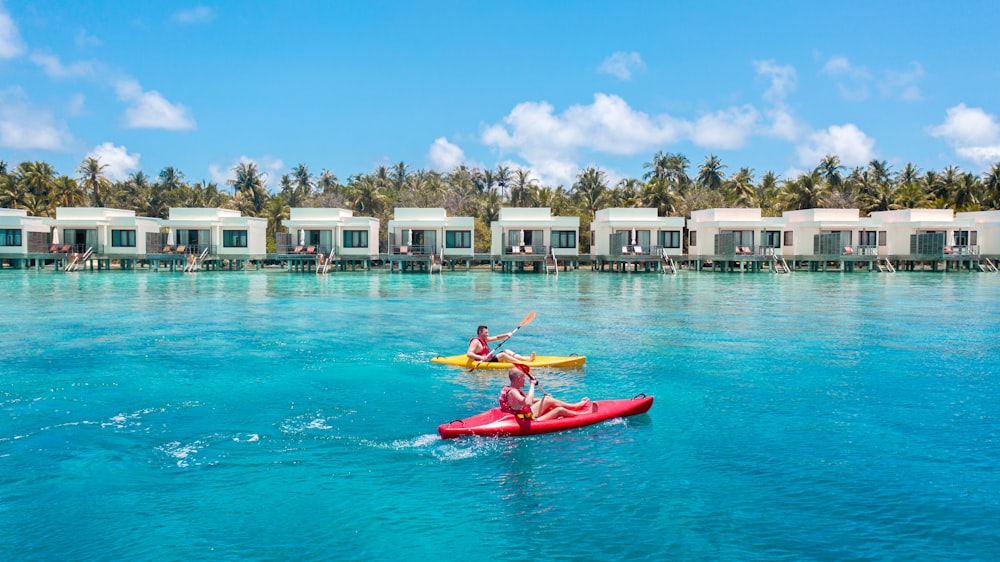 a couple of people riding on top of a red kayak