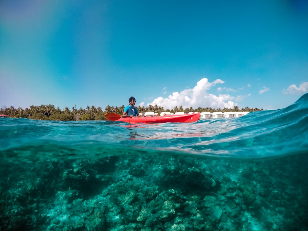 a man riding a red kayak on top of a body of water