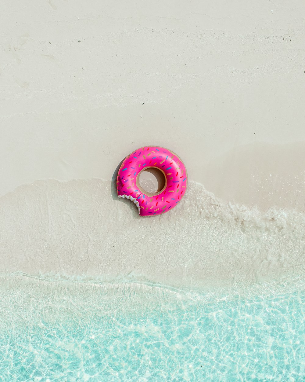 a pink donut floating on top of a body of water