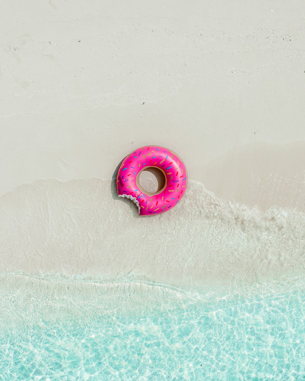 Ein rosa Donut, der auf einem Gewässer schwimmt