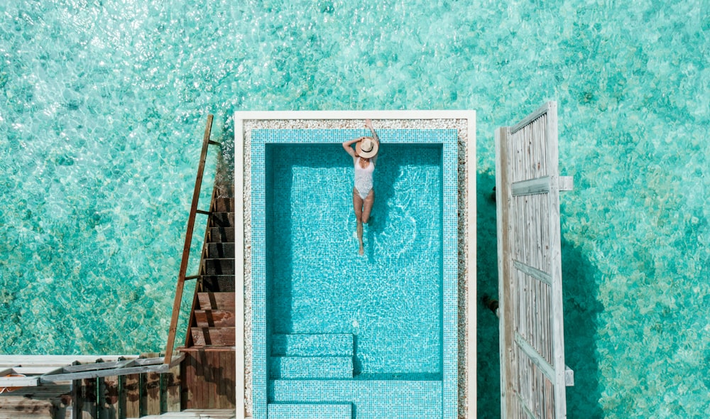 uma mulher em um chapéu está de pé em uma piscina