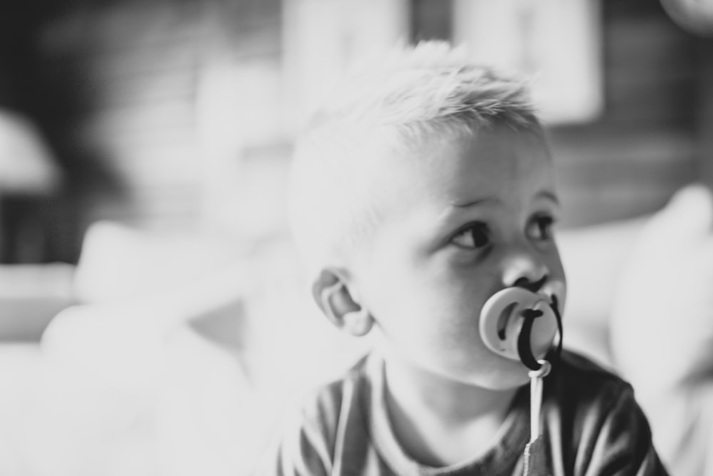 a black and white photo of a baby with a pacifier in his mouth