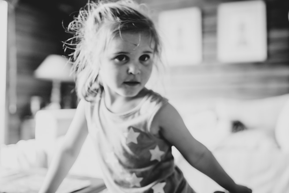 a little girl standing on top of a bed