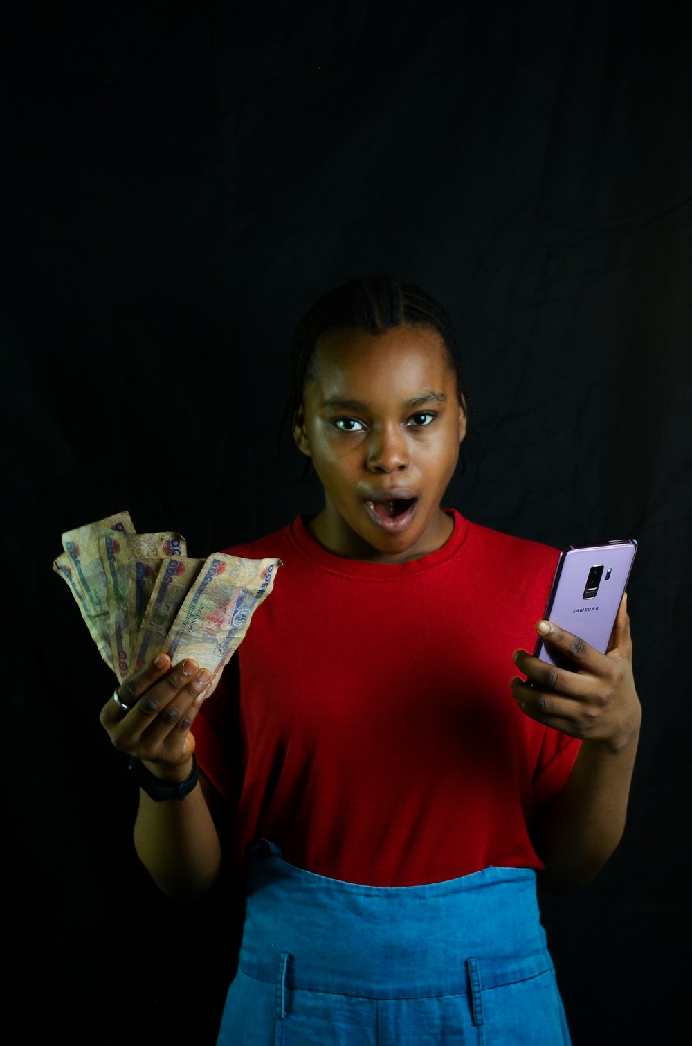 a woman holding a cell phone and a bunch of money