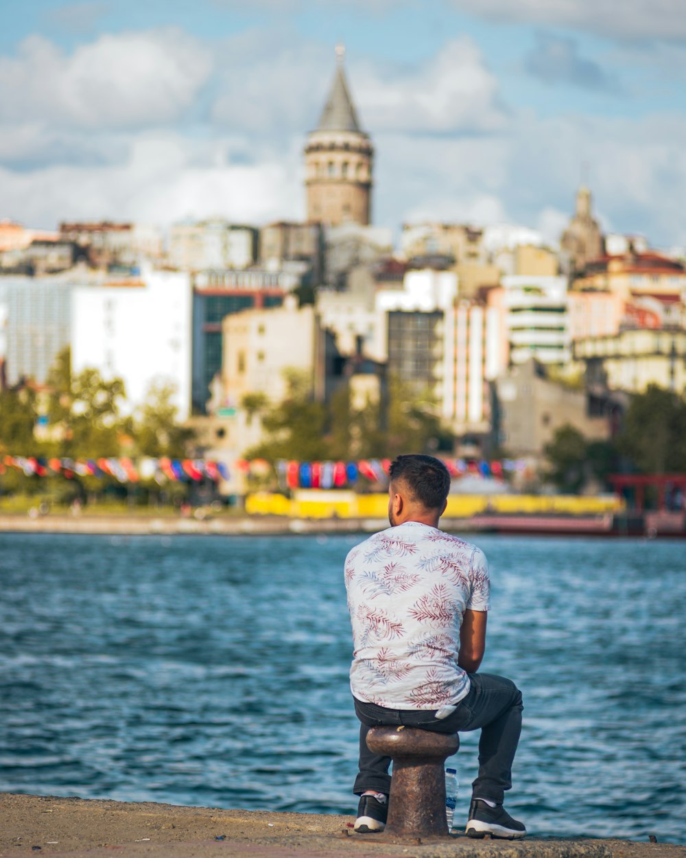 a man is sitting on a post by the water