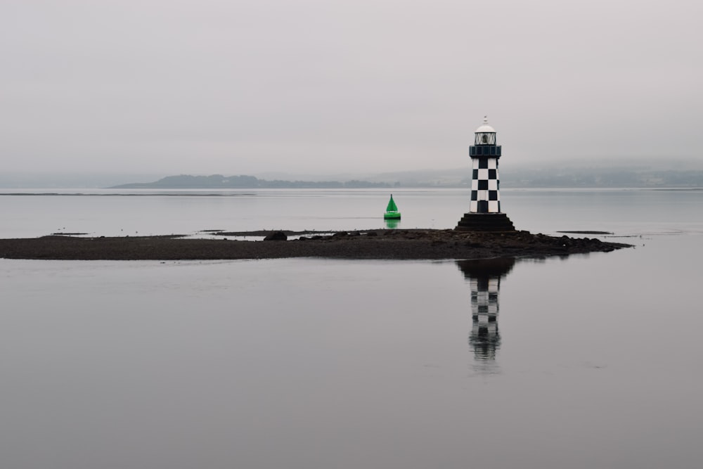 a lighthouse on a small island in the middle of a lake