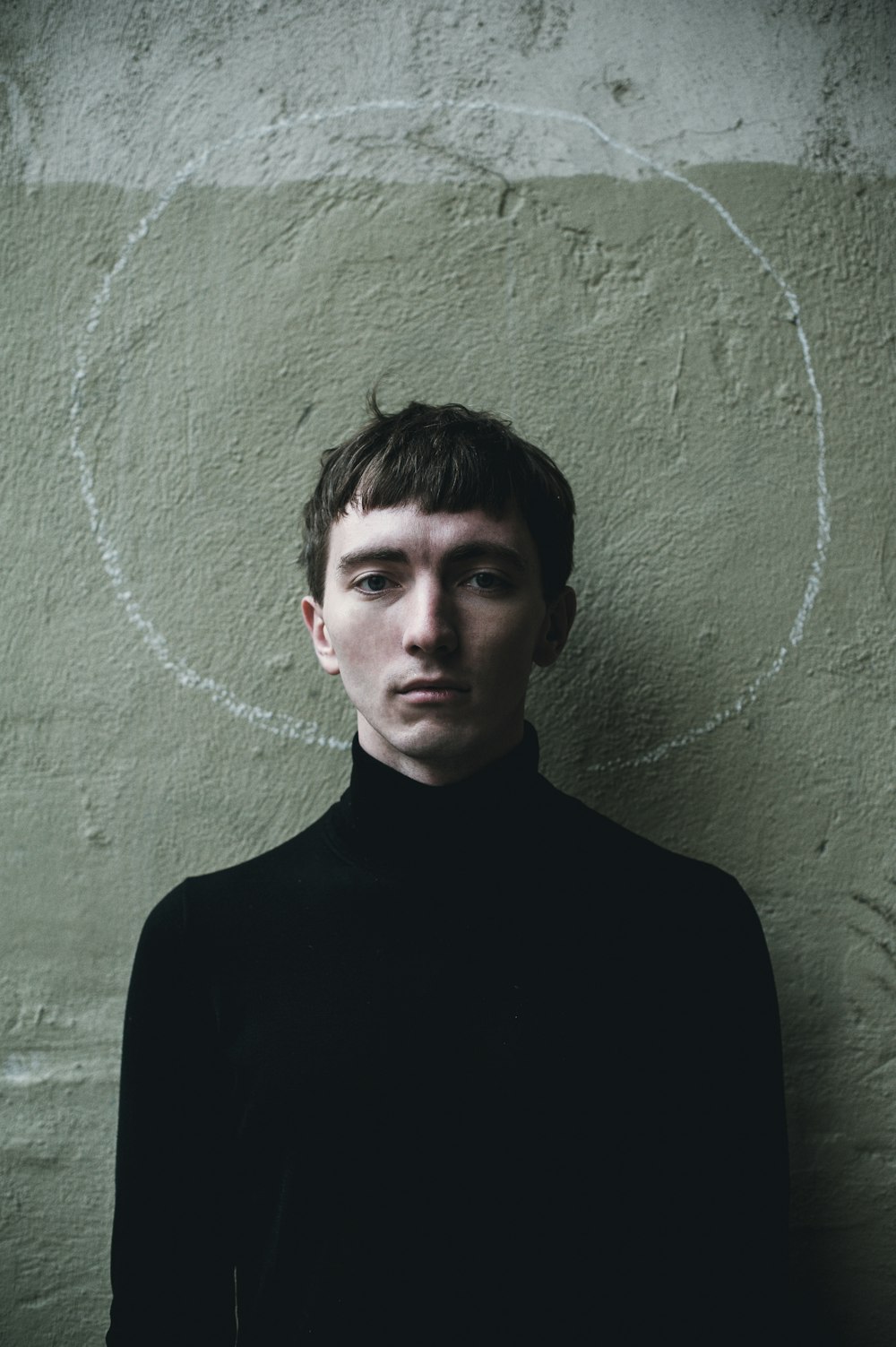 a man standing in front of a wall with a circle drawn on it