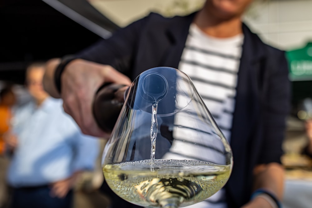 a person pouring a glass of white wine