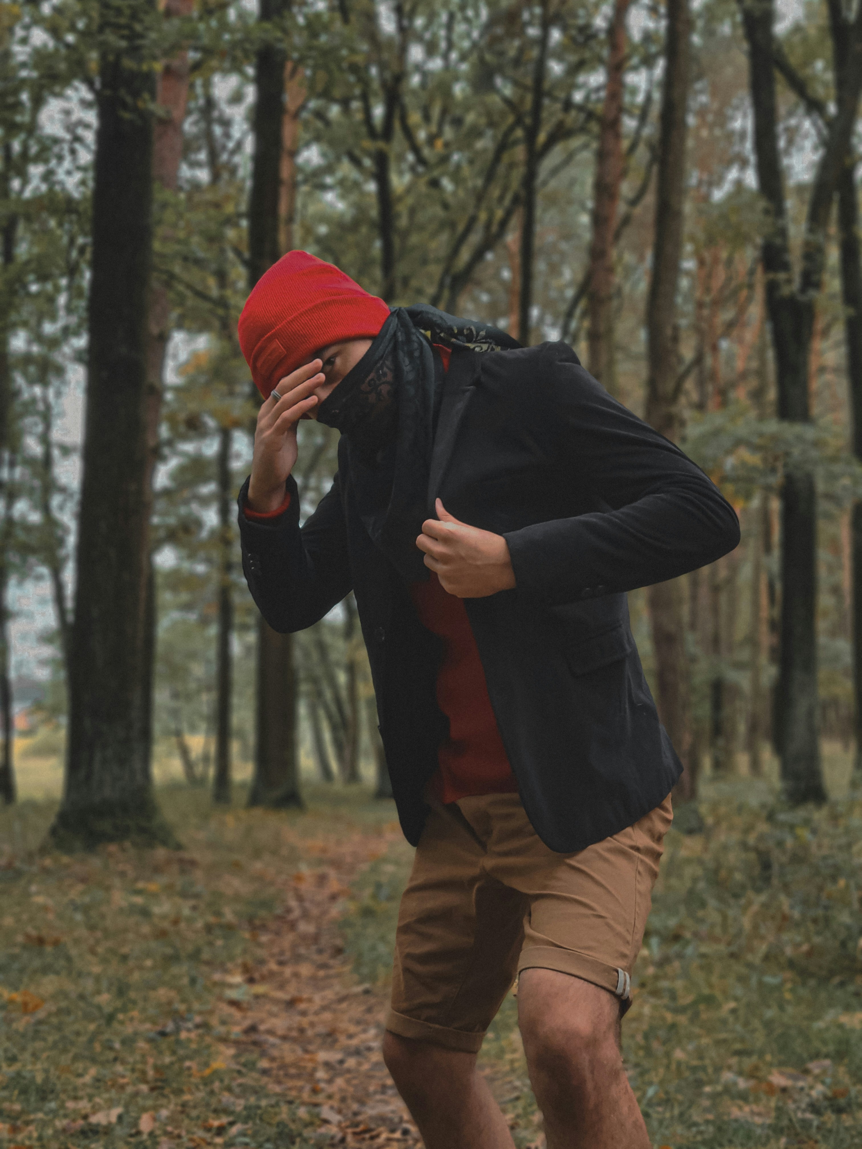 a man in a red hat is walking through the woods