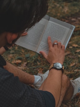 a man reading a book in the grass