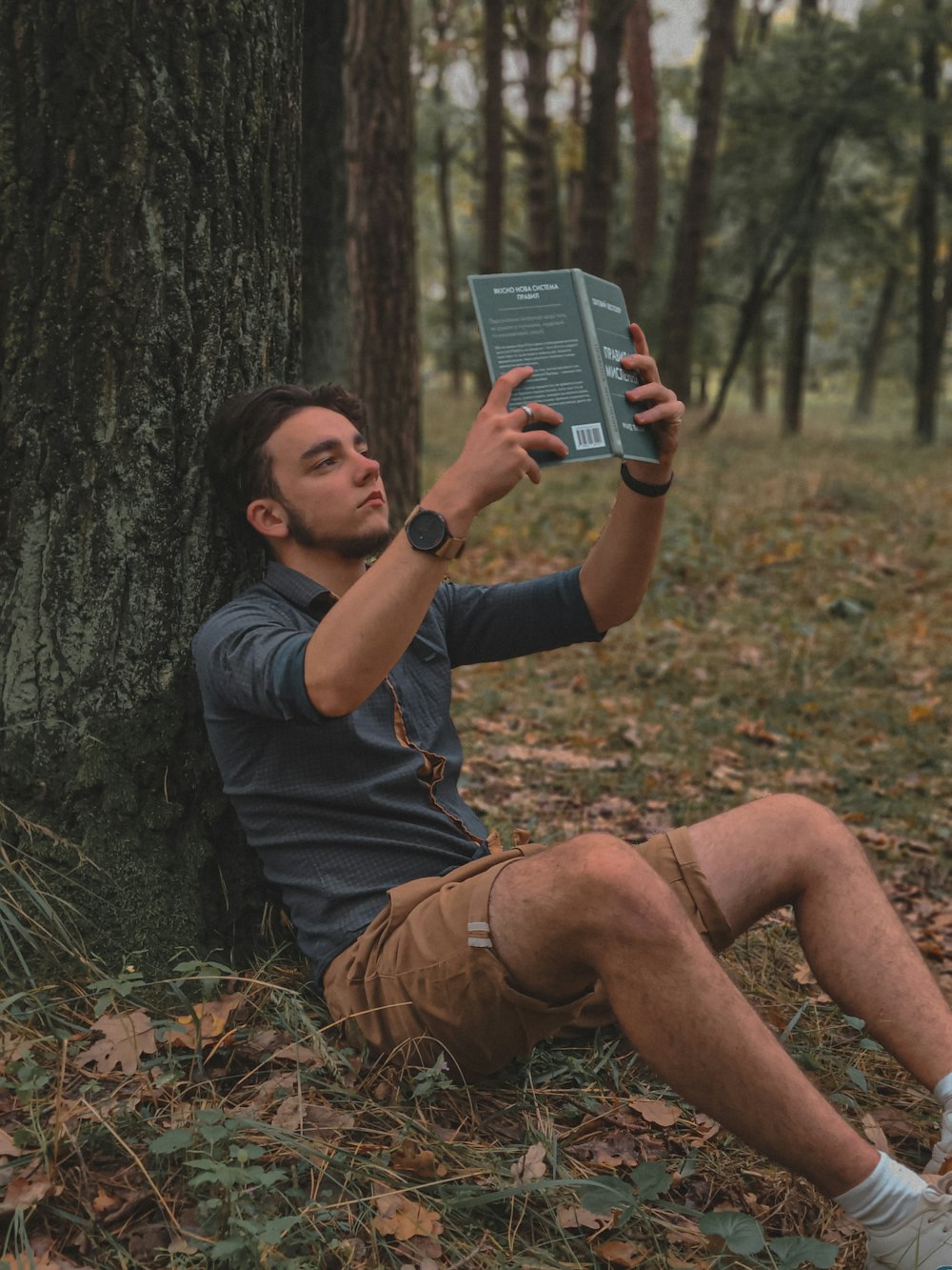 a man sitting under a tree holding a book