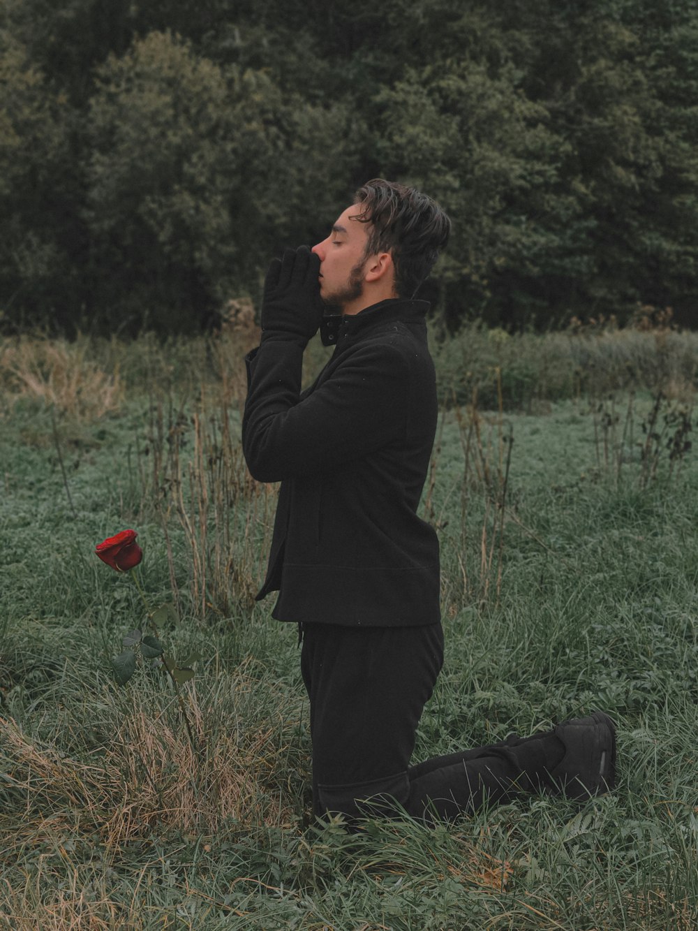 a man in a black suit and a red flower