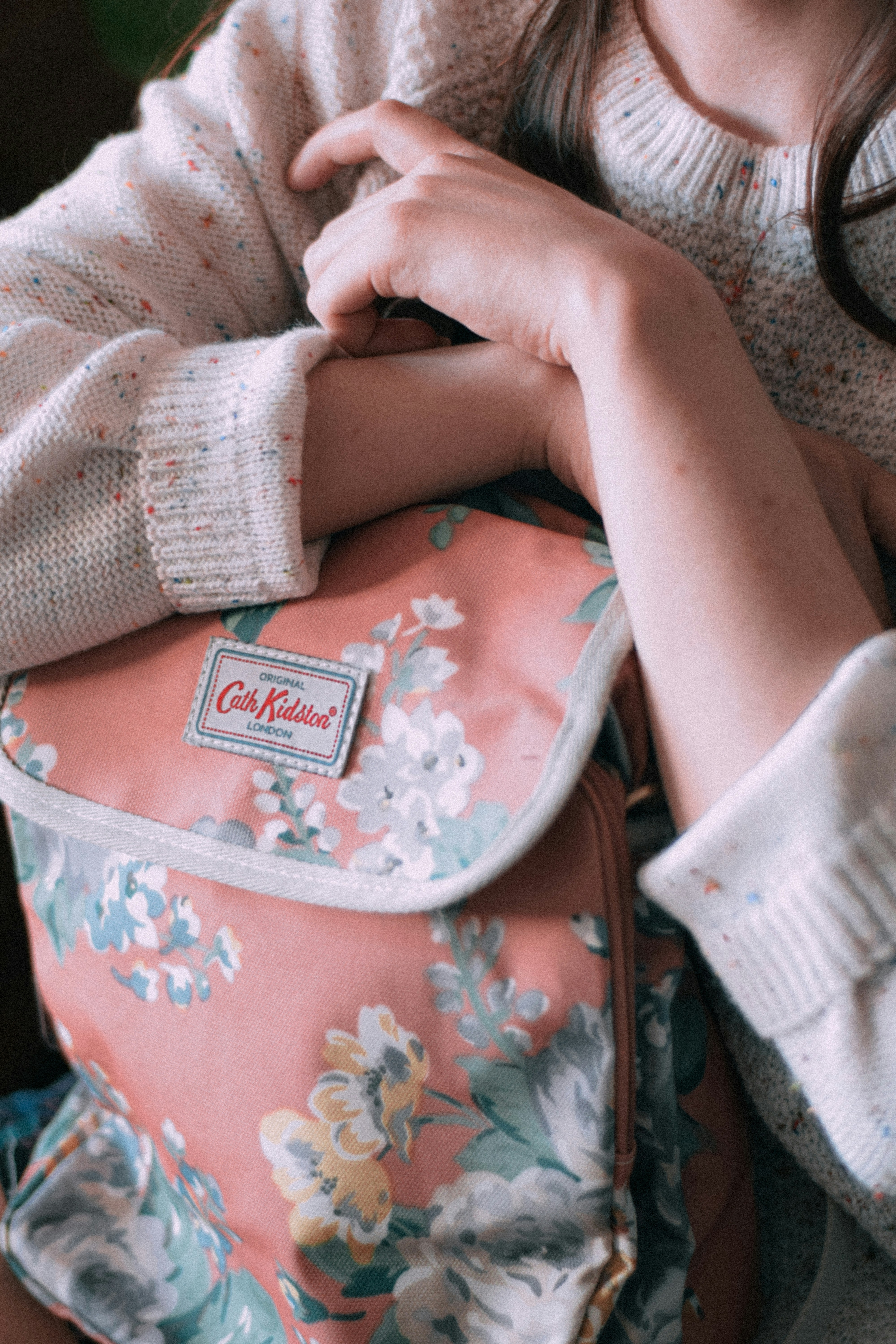 a young girl holding a pink floral backpack