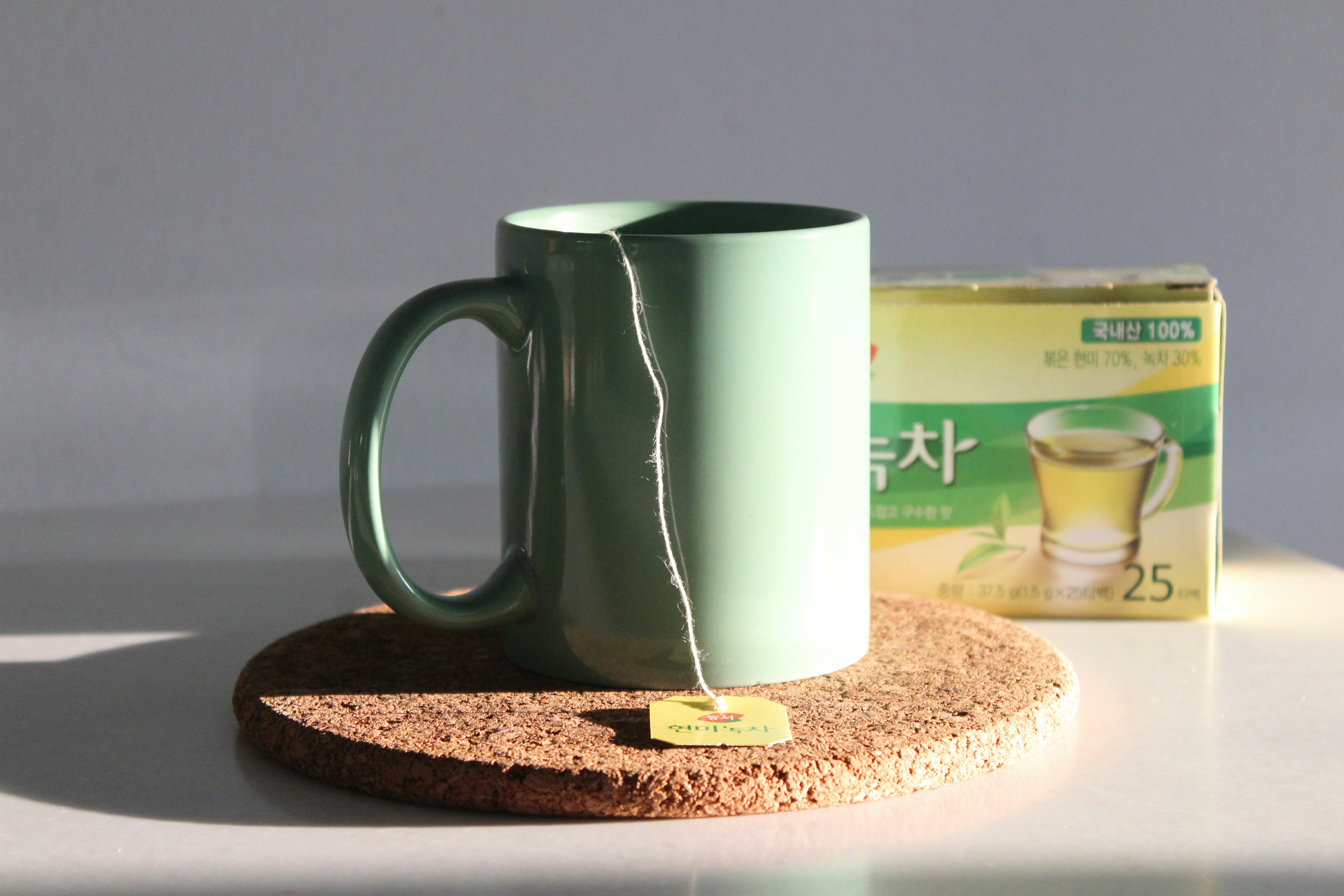 a green coffee mug sitting on top of a coaster